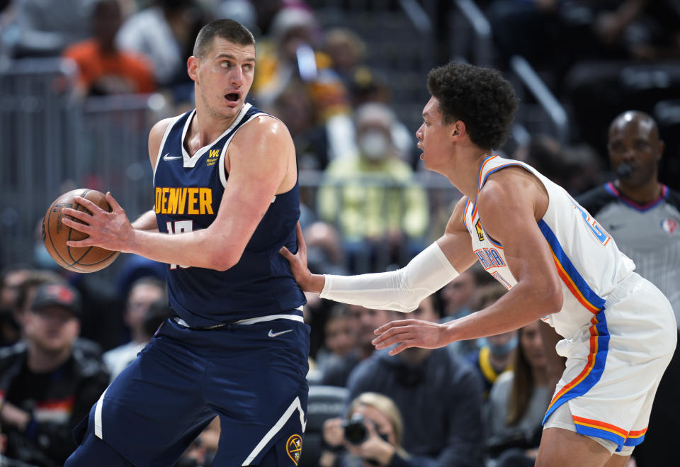 Denver Nuggets center Nikola Jokic, left, looks to pass the ball as Oklahoma City Thunder forward Isaiah Roby defends during the first half of an NBA basketball game Wednesday, March 2, 2022, in Denver. (AP Photo/David Zalubowski)