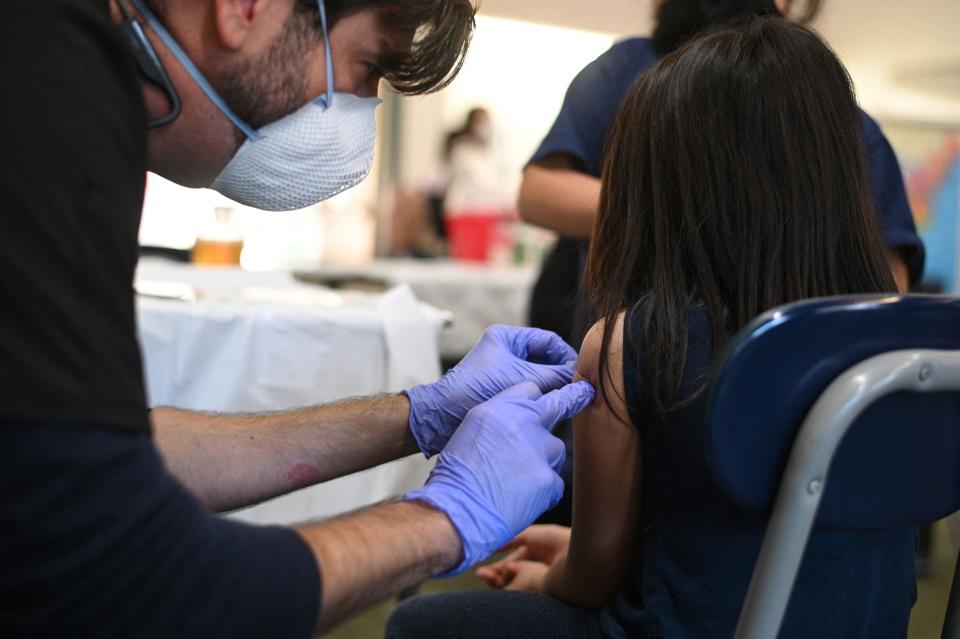 A nurse puts a bandaid on a girl's arm after administering a pediatric dose of the COVID-19 vaccine at a L.A. Care Health Plan vaccination clinic at Los Angeles Mission College in the Sylmar neighborhood in Los Angeles, California, January 19, 2022.  / Credit: ROBYN BECK/AFP via Getty Images