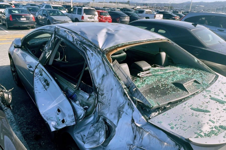 A damaged car is seen in a airport parking lot after debris from tire which fell from a Boeing 777 landed on it at San Francisco International Airport, March 7, 2024. (AP Photo/Haven Daley, File)