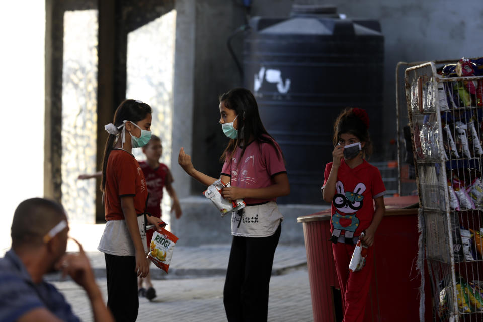 Children wear face masks while shopping at a grocery store during a lockdown imposed during the coronavirus pandemic, at Shati refugee camp, in Gaza City, Thursday, Aug. 27, 2020. On Wednesday Gaza's Hamas rulers extended a full lockdown in the Palestinian enclave for three more days as coronavirus cases climbed after the detection this week of the first community transmissions of the virus in the densely populated, blockaded territory. (AP Photo/Adel Hana)