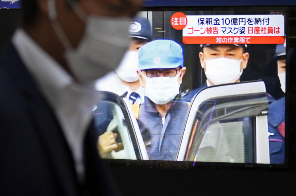 A man walks by a TV monitor which reports on former chairman of Nissan Motor Co., Carlos Ghosn, in Tokyo Wednesday, March 6, 2019. Disguised as a construction worker, Ghosn left a Tokyo detention center Wednesday after posting 1 billion yen ($8.9 million) bail. (Akiko Matsushita/Kyodo News via AP)