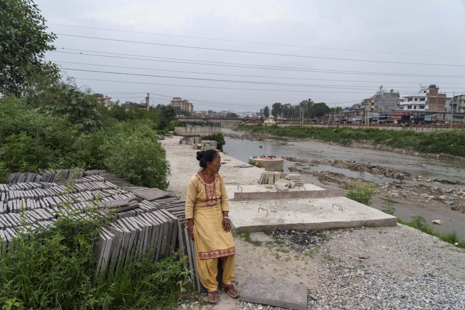 Mithu Lama, 59, rests near her house on the banks of the Bagmati River in Kathmandu, Nepal, Wednesday, June 1, 2022. Born and raised next to the Bagmati, Lama recalls using its waters for cooking, bathing, washing and even drinking. Today that feels like a long-ago dream dashed by decades of dumping human waste and refuse, and one she doesn’t expect to see again anytime soon. (AP Photo/Niranjan Shrestha)