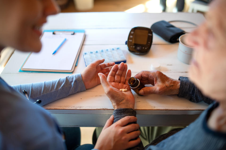 A medical professional is speaking with their older patient as they take their medication