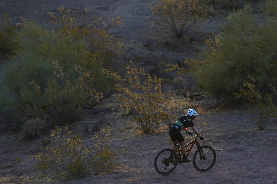 A cyclist pedals through the desertscape in Papago Park at sunrise as temperatures are expected to hit 115-degrees F. (46 C.), Monday, July 17, 2023, in Phoenix. (AP Photo/Ross D. Franklin)