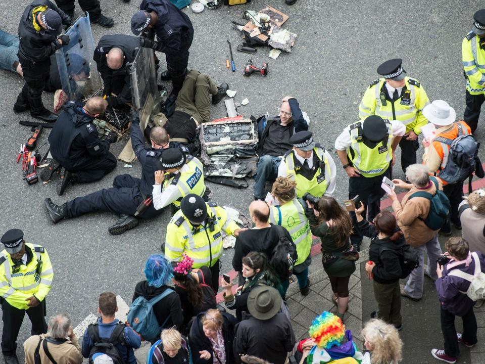 Police work to remove protesters who blocked an access road to the 2017 Defence and Security Equipment International (DSEI) arms fair by chaining themselves together on 6 September 2017 (Getty Images)