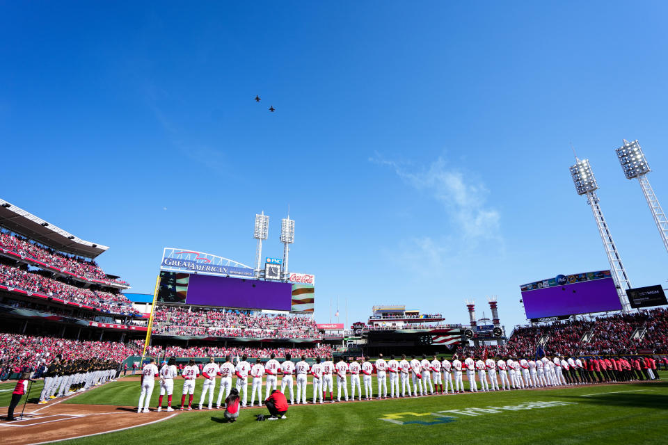 Players stand for the National Anthem as F-16s fly over the field for the 104th Cincinnati Reds Opening Day against the Pittsburgh Pirates on Thursday March 30, 2023.