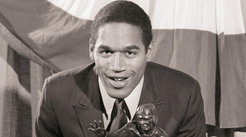 12/5/1968-New York, NY- O.J. Simpson, of Southern California, the most celebrated collegiate football player of 1968, looms over the Heisman Memorial Trophy Dec. 5th, after he received the award. During the day, Simpson also was selected United Press International Player of the Year. - Photo: Getty Images (Getty Images)