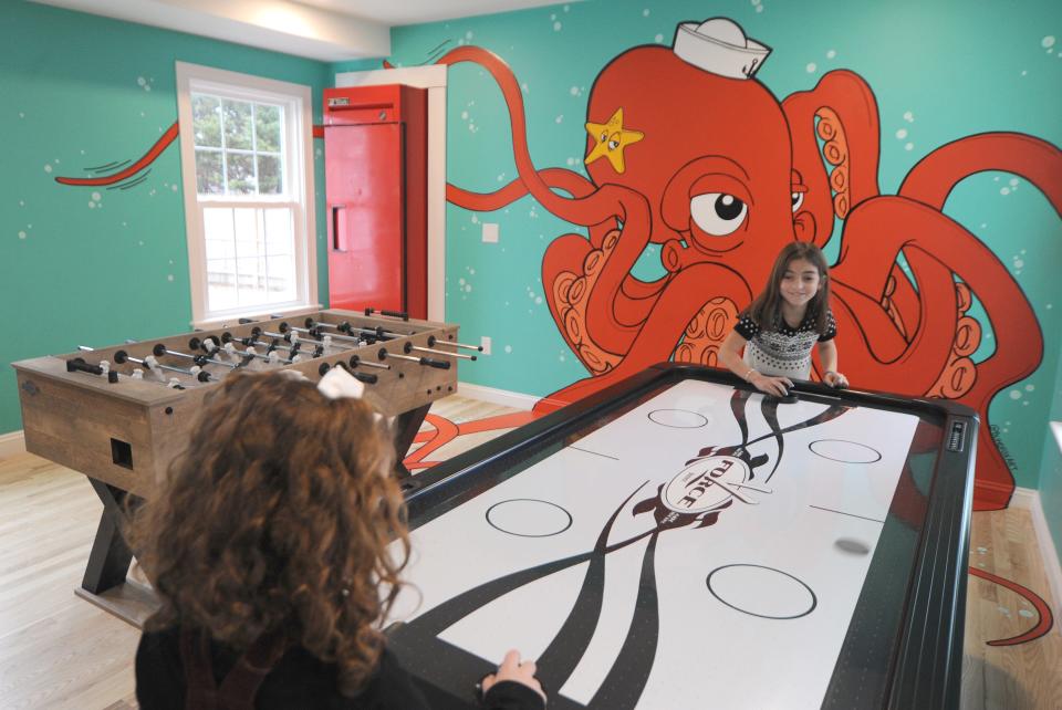 Inside the game room, sisters Lucyanna Criscuolo, 10, left, and Mia Rae Criscuolo, 8, play air hockey on Feb. 13, 2022. The Criscuolo family is from Stoughton and stayed at Tommy's Place.