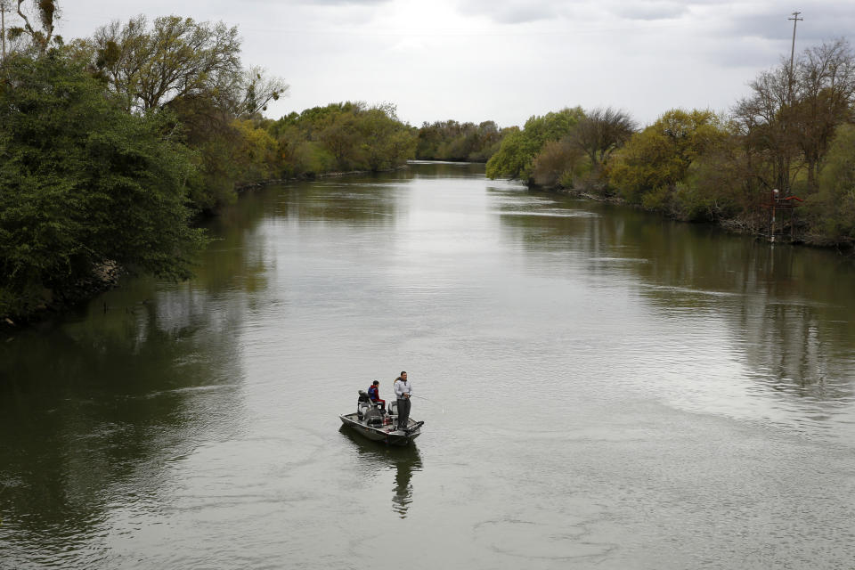 FILE - People fish in the Sacramento-San Joaquin River Delta's Elk Slough near Courtland, Calif., Tuesday, March 24, 2020. A proposal in the California state Senate aims to keep more water in California's rivers and streams to benefit endangered species of fish. Under the plan the state would spend up to $1.5 billion to buy up "senior water rights" that farmers use to take water from the state's rivers and streams to grow their crops. (AP Photo/Rich Pedroncelli, File)