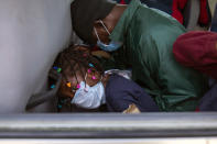 Haitians who were deported from the United States hide their faces as they arrive at a hotel where they will be quarantined as a measure against the spread of the new coronavirus, in Tabarre, Haiti, April 23, 2020. (AP Photo/Dieu Nalio Chery)