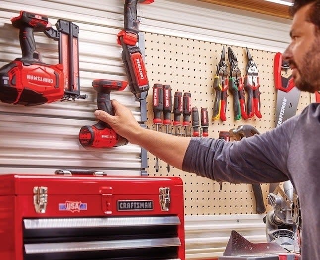 a person putting the tools on a shed wall