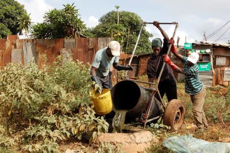 Kenyan 'froggers' slum dwellers Godfrey Ndalo and Patrick Osunda are assisted as they empty a metallic barrel of excrement from a pit latrine into a manhole in Kibera slum within Nairobi, Kenya February 24, 2019. REUTERS/Njeri Mwangi