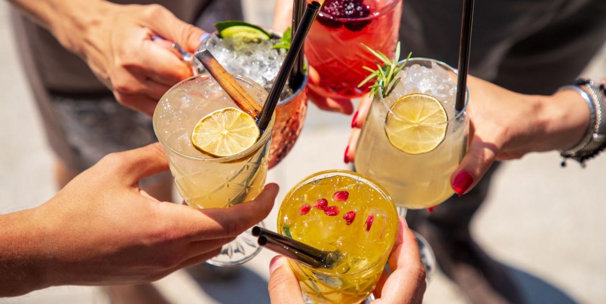 five cocktails in hands joined in celebratory toast