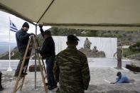 An army officer watches the preparations for Friday's visit of German and Greek Presidents, at the monument with the names of villagers who German army troops massacred, in the village of Ligiades near the northwestern town of Ioannina, Greece, on Thursday, March 6, 2014. German President Joachim Gauck's three-day visit to the country will include a speech Friday at the site where German army troops massacred 92 villagers near the northeastern town of Ioannina, and a meeting with the town's Jewish community. (AP Photo/Thanassis Stavrakis)