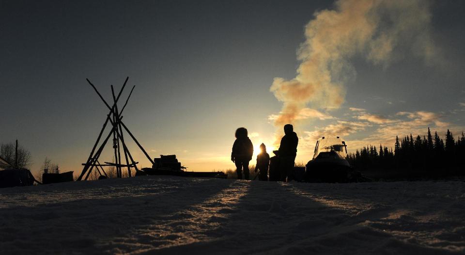 Nikolai residents Oline Petruska, Tyler Alexia and Stephanie Petruska wait by the wood fired hot water for mushers to come in at the Nikolai checkpoint during the 2014 Iditarod Trail Sled Dog Race at sunrise on Wednesday, March 5, 2014. (AP Photo/The Anchorage Daily News, Bob Hallinen)