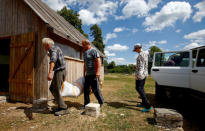 Yuri Baikov, 69, his daughter Veronika and her friend unload fodder for poultry at his small farm, situated in a forest near the village of Yukhovichi, Belarus, June 21, 2018. REUTERS/Vasily Fedosenko