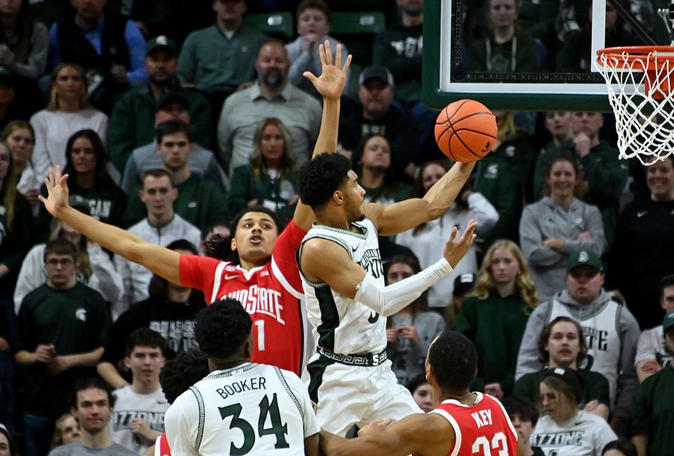 Michigan State Spartans guard Jaden Akins (3) scores past Ohio State Buckeyes forward Devin Royal (21) during the first half at Breslin Center in East Lansing on Sunday, Feb. 25, 2024.