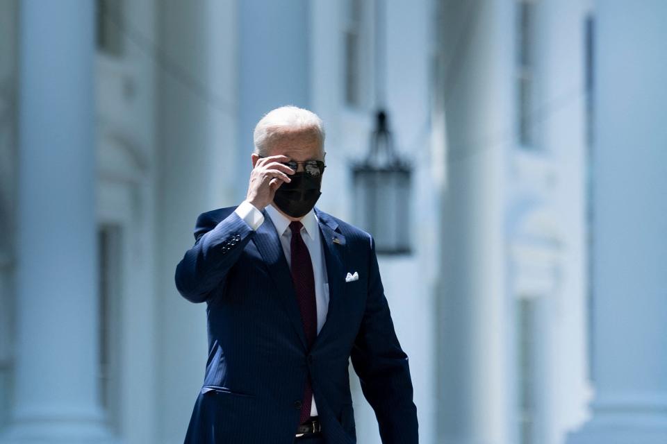 President Joe Biden removes his sunglasses while walking to an event in front of the White House about updated guidelines on masks for people who are fully vaccinated.