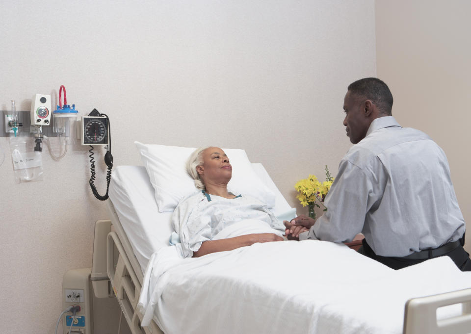 woman in a hospital bed while her husband sits with her