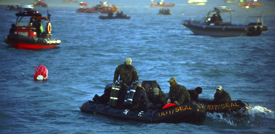 In this Tuesday, April 22, 2014, searchers and divers look for people believed to have been trapped in the sunken ferry Sewol in the water off the southern coast near Jindo, south of Seoul, South Korea. One by one, coast guard officers carried the newly arrived bodies covered in white sheets from a boat to a tent on the dock of this island, the first step in identifying a sharply rising number of corpses from the South Korean ferry that sank nearly a week ago. (AP Photo/Korea Pool) KOREA OUT