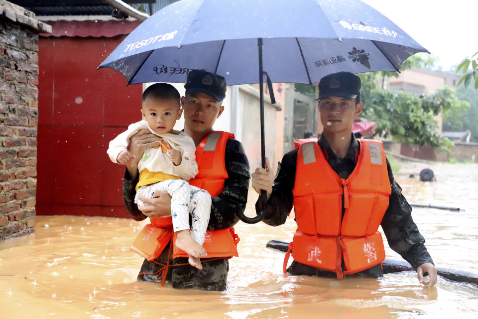 Rescuers carry a child to a boat during an evacuation of a flooded village in Qingyuan in southern China's Guangdong province on Monday, June 8, 2020. Flooding in south and central China has lead to more than a dozen deaths and forced hundreds of thousands of people from their homes, the government said Wednesday. (Chinatopix Via AP)