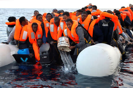 Sub-Saharan migrants are seen aboard an overcrowded raft, as one of them uses a bucket to remove water from the raft. REUTERS/Giorgos Moutafis