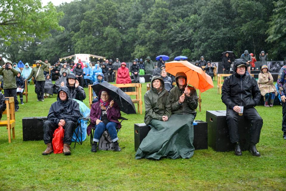 Festival-goers shelter from the rain as Storm Lilian approaches during the Toender Festival, in Toender, Jutland, Denmark (EPA)