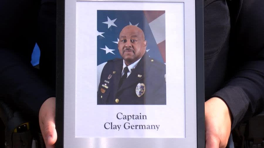 A law enforcement officer holds the picture of Captain Clay Germany during a memorial service in Wichita on May 15, 2024. (KSN News Photo)