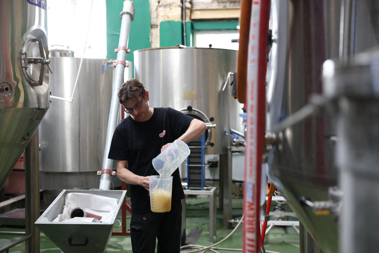 Head brewer at the Exale Brewing and Taproom, Josh Walker, 37, shows how to check the specific gravity of the beer which indicates its stage of formation and alcohol content, at the brewery plant, in East London, on August 19, 2022. - The brewery boom started thanks to a tax shelter that gives a 50% tax rebate to breweries that produce less than 4000 hl per year, which, combined with relatively low installation costs, has allowed the emergence of hundreds of establishments in 20 years: 1900 last year in the United Kingdom, almost 5 times more than in the early 2000s. But according to the CAMRA, an association of British craft brewers interviewed by AFP, the boom in craft breweries in the country, is already slowing down and the closing of some establishments could accelerate due to cost inflation, particularly in energy. (Photo by Hollie ADAMS / AFP) (Photo by HOLLIE ADAMS/AFP via Getty Images)