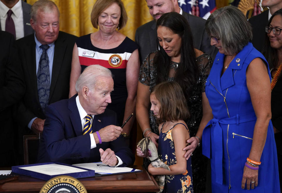 Image: President Joe Biden, after signing the PACT Act of 2022, gifts his pen to Brielle Robinson, the daughter of Sgt. 1st Class Heath Robinson, who died of cancer two years prior. (Evan Vucci / AP file)