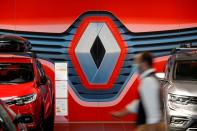 FILE PHOTO: An employee walks past a logo of Renault carmaker at a dealership in Nantes