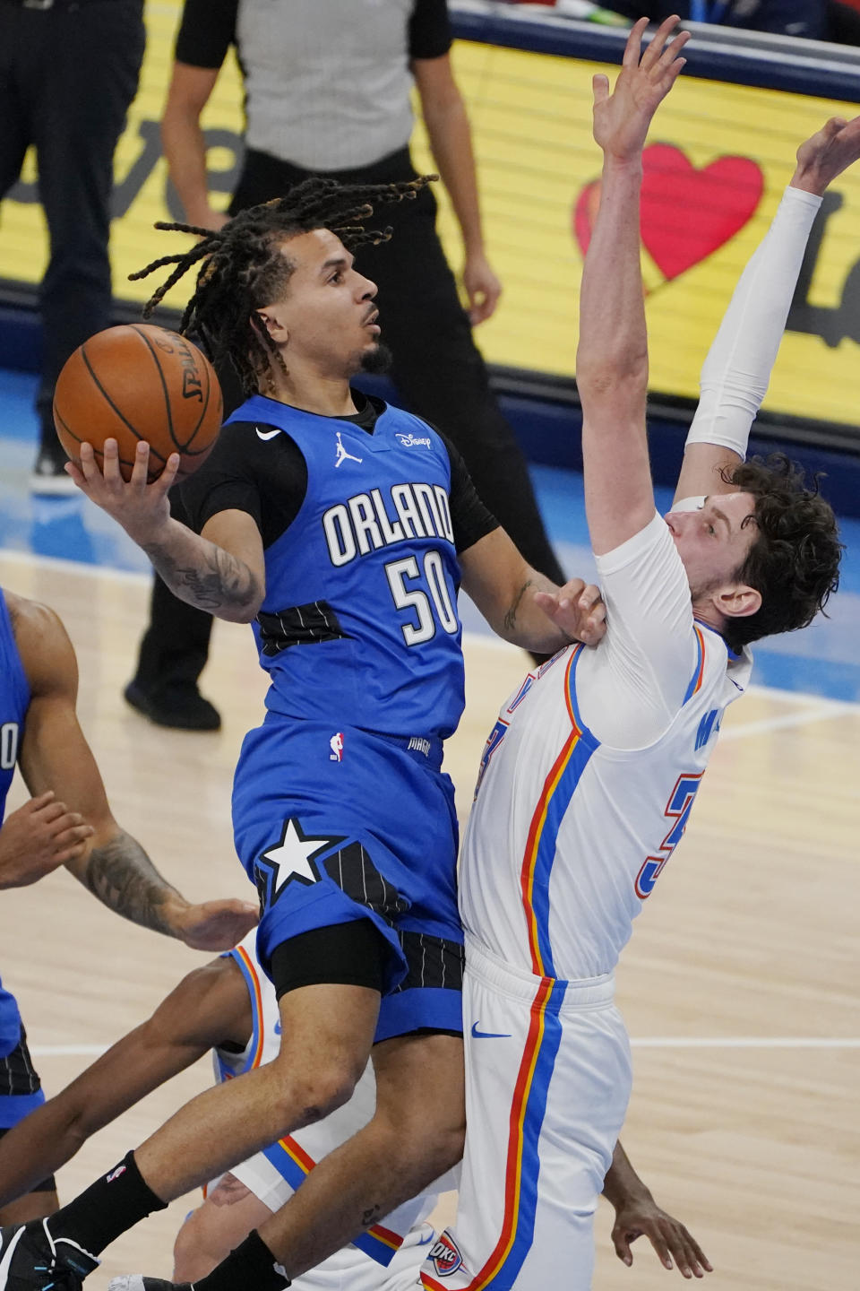 Orlando Magic guard Cole Anthony (50) goes to the basket past Oklahoma City Thunder forward Mike Muscala, right, in the first half of an NBA basketball game Tuesday, Dec. 29, 2020, in Oklahoma City. (AP Photo/Sue Ogrocki)