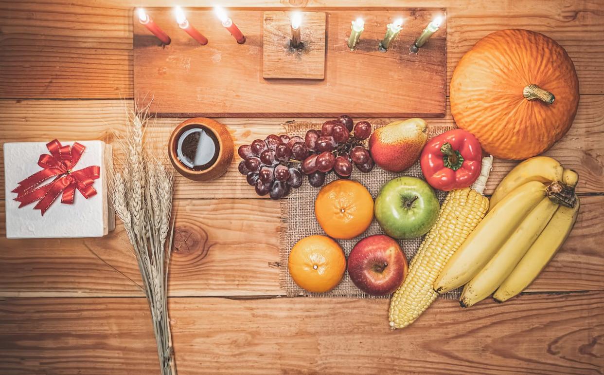 kwanzaa holiday concept with decorate seven candles red, black and green, gift box, pumpkin,corn and fruit on wooden desk and background