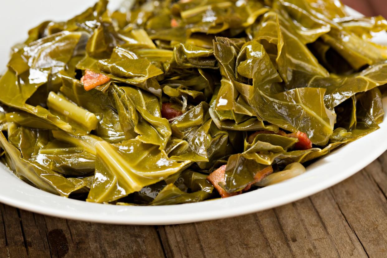 Cooked collard greens in a white bowl and prepared with ham hocks