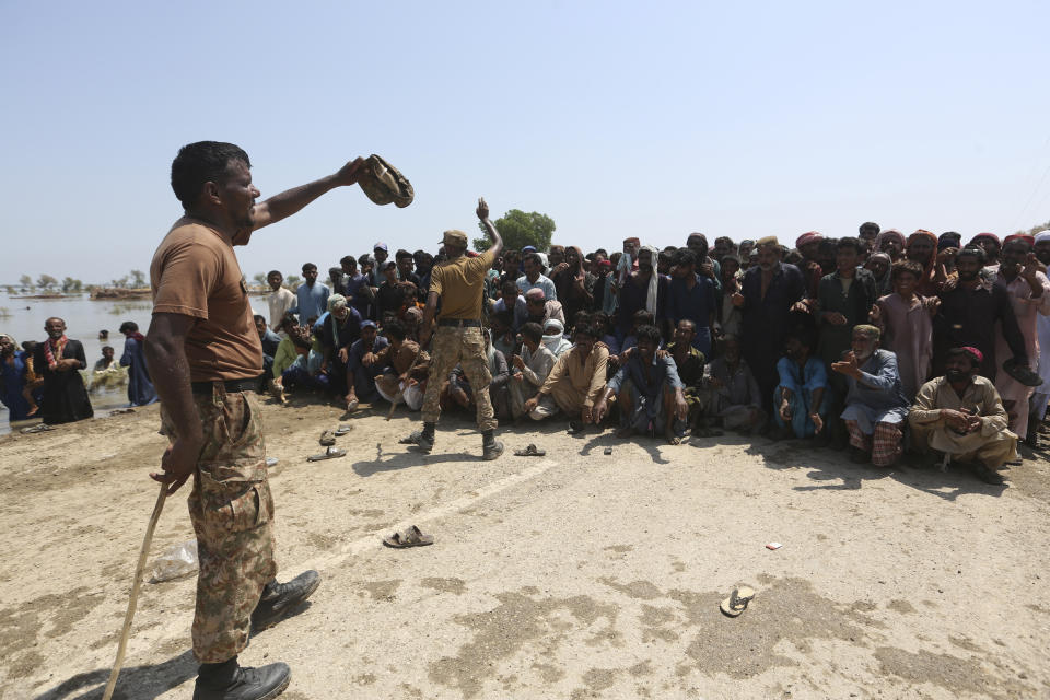 Victims of heavy flooding from monsoon rains wait to receive relief aid from the Pakistani Army in the Qambar Shahdadkot district of Sindh Province, Pakistan, Friday, Sept. 9, 2022. U.N. Secretary-General Antonio Guterres appealed to the world for help for cash-strapped Pakistan after arriving in the country Friday to see the climate-induced devastation from months of deadly record floods. (AP Photo/Fareed Khan)