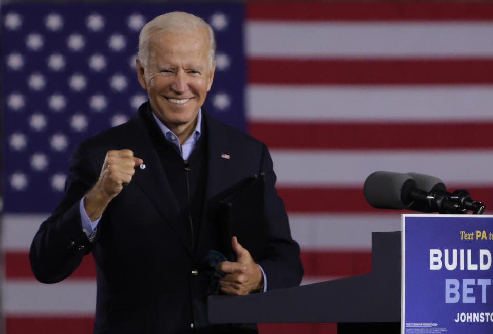 Joe Biden smiles at a podium in front of an American flag
