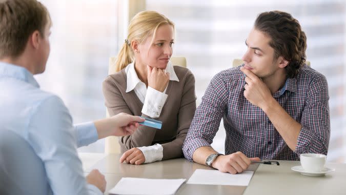 Young serious couple thinking over high housing costs, rent levels and security of tenancy, trying to buy a home with a minimal down payment, calculating monthly budget, pay with card.