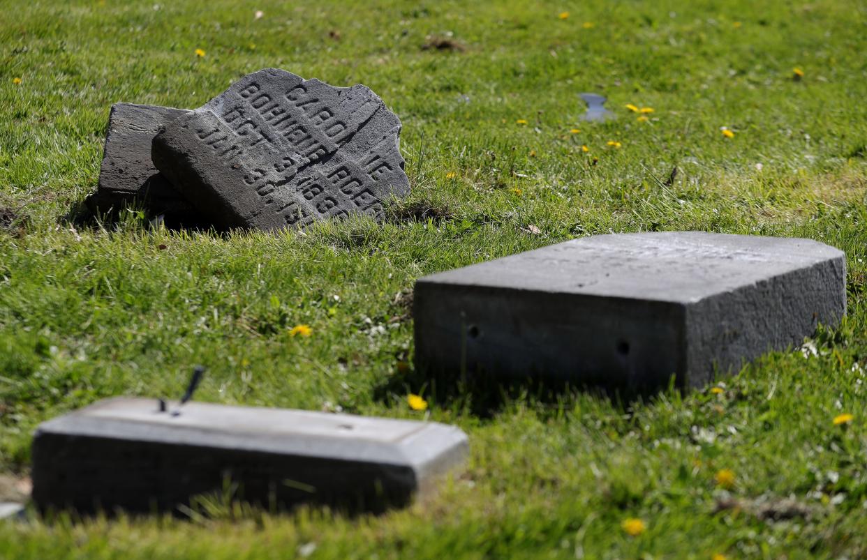 Headstones are left toppled on the ground Monday, April 22, 2024, after a motorist crashed through St. Bernard Catholic Cemetery over the weekend in Akron, Ohio.