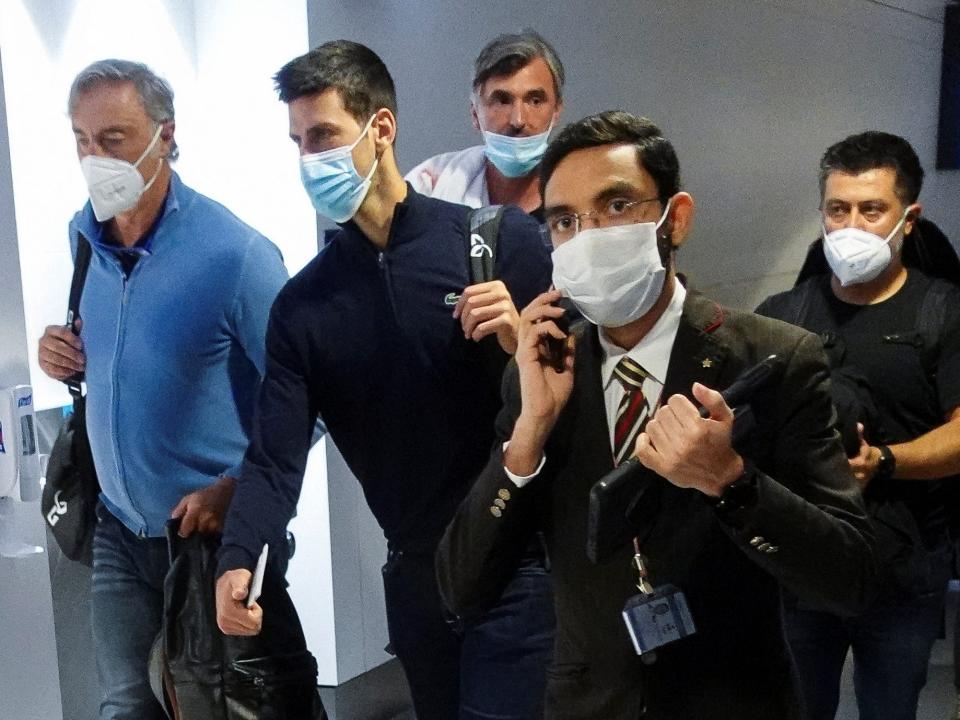 Novak Djokovic walks through Dubai Airport surrounded by his team