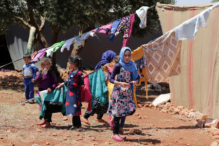 FILE PHOTO: Children stand together near hanging clothes in an olive grove in the town of Atmeh, Idlib province, Syria May 19, 2019. REUTERS/Khalil Ashawi