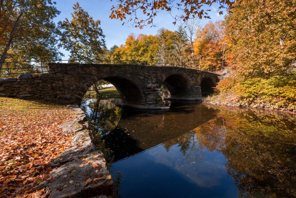 stone arch bridge in callicoon, ny, catskill mountains, surrounded by brilliant fall foliage on a bright autumn morning