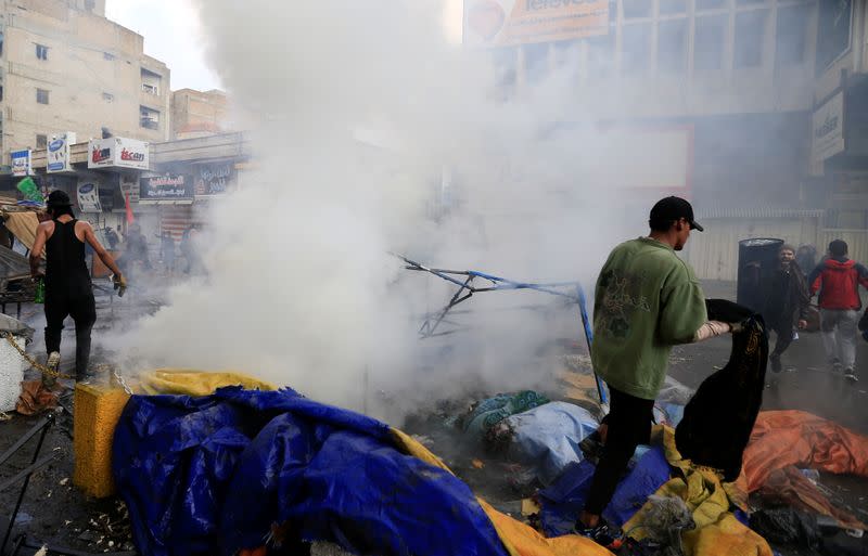 Demonstratos are seen amongst smoke rising from burning tents as Iraqi security forces raid at Tahrir Square during ongoing anti-government protests in Baghdad