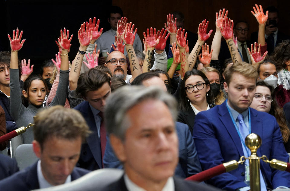 Anti-war protesters raise painted hands behind U.S. Secretary of State Antony Blinken during a Senate Appropriations Committee hearing on President Biden's $106 billion national security supplemental funding request to support Israel and Ukraine, as well as bolster border security, on Capitol Hill in Washington, U.S., on Oct. 31, 2023. <span class="copyright">Kevin Lamarque—Reuters</span>