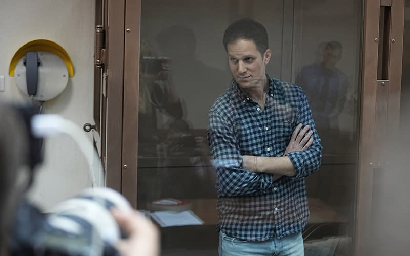 Wall Street Journal reporter Evan Gershkovich stands in a glass cage in a courtroom