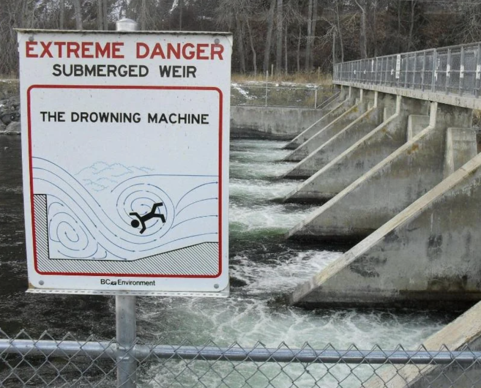 Warning sign by river illustrating the danger of a submerged weir known as "The Drowning Machine."