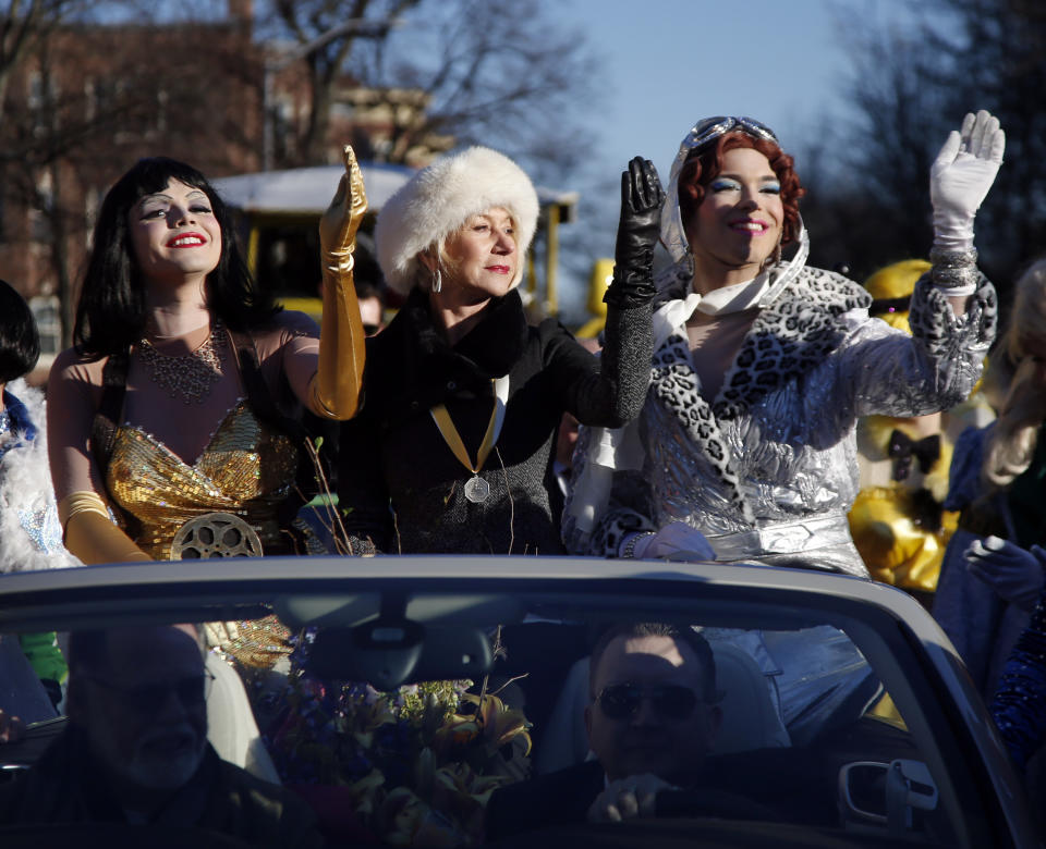 Actress Helen Mirren waves like a queen, accompanied by drag actors Tony Oblen, left, and Ethan Hardy, right, as she is paraded through Harvard Square as woman of the year by Harvard University's Hasty Pudding Theatricals in Cambridge, Mass., Thursday, Jan. 30, 2014. (AP Photo)