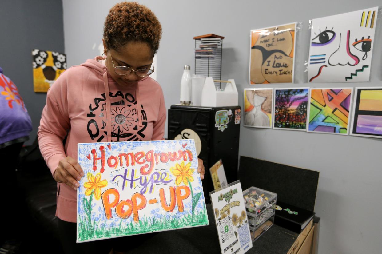 Nnenia “Reminisce X” Okereke holds the original sign used for their pop-up events Wednesday, Sept. 27, 2023, at Homegrown Hype studios on South Michigan Street in South Bend.