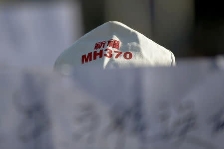 FILE PHOTO: A family member of a passenger onboard Malaysia Airlines flight MH370 which went missing in 2014 holds a banner during a gathering in front of the Malaysian Embassy on the second anniversary of the disappearance of MH370, in Beijing, China, March 8, 2016. REUTERS/Damir Sagolj/File Photo