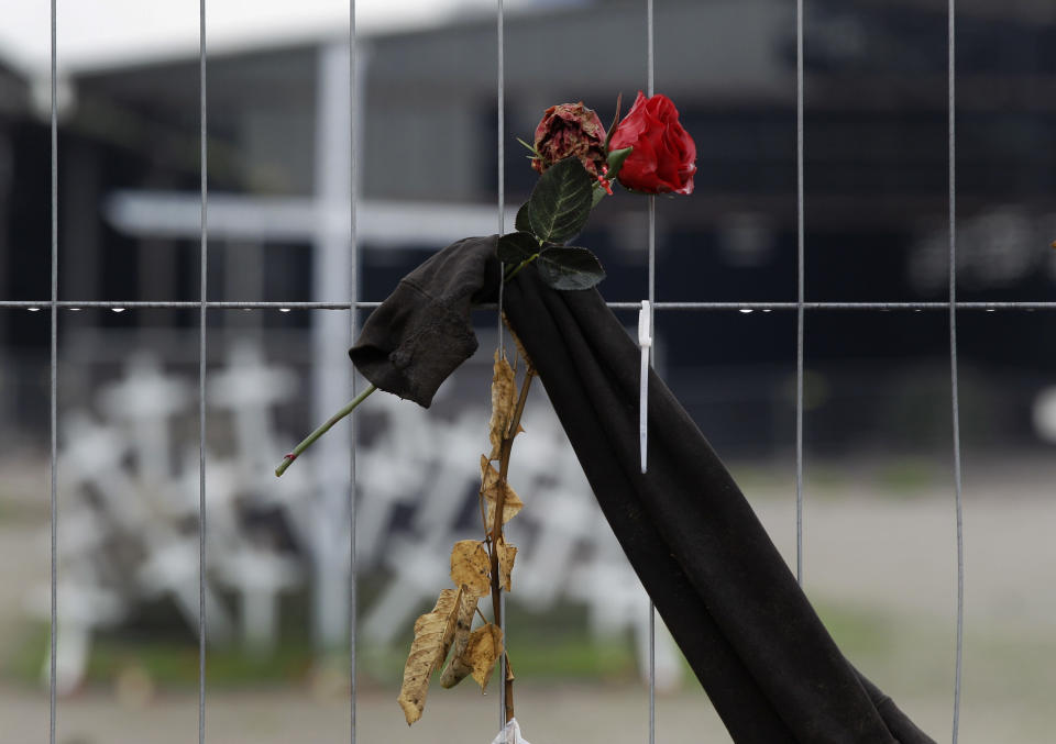 FILE - In this Aug. 23, 2010 file picture a rose is fixed to a fence in front of crosses near the site where 21 people died a in a stampede during the Love Parade in Duisburg, western Germany, German prosecutors say they have indicted 10 people on charges including involuntary manslaughter over a mass panic at the Love Parade techno music festival nearly four years ago that resulted in 21 deaths. Duisburg prosecutor Horst Bien said Wednesday Feb. 12, 2014 that four employees of the event's organizers and six city workers have been indicted. They face charges of involuntary manslaughter and bodily harm, punishable with up to five years jail time. (AP Photo/Frank Augstein,File)