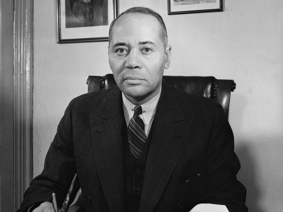 Black and white photo of Charles Hamilton Houston in a suit sitting on an office chair.